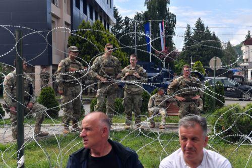 epa10668340 People sit in front of soldiers of the US contingent of the NATO-led international peacekeeping Kosovo Force (KFOR) while they take positions in front of the municipality building in Leposavic, Kosovo, 02 June 2023. At least thirty KFOR peacekeepers and fifty two civilians were injured in clashes between security forces and ethnic Serbs in...