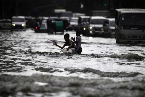 epa10830560 Children frolic on a flooded street in Manila, Philippines, 31 August 2023. Typhoon Saola, which has left the Philippine Area of Responsibility, and Tropical Storm Haikui off the coast of extreme northern provinces are enhancing a southwest monsoon bringing rains in the western Luzon region of the country, according to data from the Philippine...