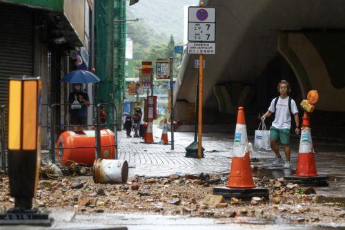 epa10847738 People walk near debris strewn across a street, following torrential rains hitting the city, in Hong Kong, China, 08 September 2023. The government has stopped schools and several public services while bus services of a major operator have been suspended, amid a black rainstorm alert, the highest level of the city's weather system.  EPA/DANIEL...