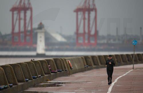 epa10885886 A person jogs along the promenade in New Brighton, Britain, 27 September 2023. Storm Agnes is expected to bring heavy rain and strong winds as it hits Britain, with yellow weather warnings covering much of the country.  EPA/ADAM VAUGHAN