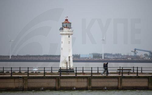 epa10885889 People walk past New Brighton Lighthouse in New Brighton, Britain, 27 September 2023. Storm Agnes is expected to bring heavy rain and strong winds as it hits Britain, with yellow weather warnings covering much of the country.  EPA/ADAM VAUGHAN