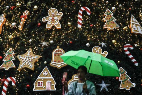 epa11015360 A woman takes a selfie picture with decorations of the tallest Christmas tree replica in Malaysia standing at 32 meters in height at the Petronas Twin Towers in Kuala Lumpur, Malaysia, 07 December 2023. Christmas is celebrated in Malaysia and across the world on 25 December.  EPA/FAZRY ISMAIL