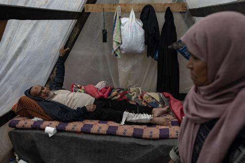 epaselect epa11107829 An injured internally displaced Palestinian man lies on a bed at Rafah Camp, southern Gaza Strip, 27 January 2024. Since 07 October 2023, up to 1.9 million people, or more than 85 percent of the population, have been displaced throughout the Gaza Strip, some more than once, according to the United Nations Relief and Works Agency for...