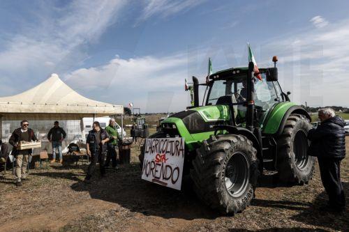 epa11134023 People stand next to a tractor with a placard that reads 'Agriculture is dying' as tractors line up during a farmers protests in Nomentana street, Rome, Italy, 07 February 2024. Farmers in Italy continue to protest against what they say are harmful European agricultural policies, echoing demonstrations in other parts of Europe, including...