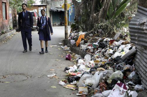 epa11165654 Students walk past plastic waste dumped along a street in Kolkata, eastern India, 19 February 2024. The volume of plastic waste is growing and it has turned into a big peril for India's cities, clogging sewers, drains and polluting water bodies.  EPA/PIYAL ADHIKARY
