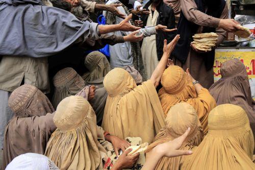 epa11229163 Burqa-clad women receive free food distributed by locals to break their fast, during the fasting month of Ramadan in Peshawar, Pakistan, 19 March 2024. The Muslims' holy month of Ramadan is the ninth month in the Islamic calendar and it is believed that the revelation of the first verse in the Koran was during its last 10 nights. It is...