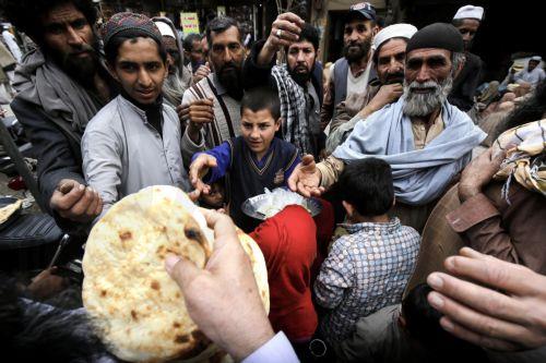 epa11229210 People receive free food distributed by locals to break their fast, during the fasting month of Ramadan in Peshawar, Pakistan, 19 March 2024. The Muslims' holy month of Ramadan is the ninth month in the Islamic calendar and it is believed that the revelation of the first verse in the Koran was during its last 10 nights. It is celebrated yearly...