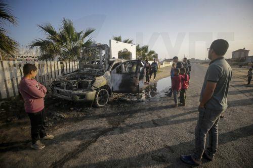 epa11255132 People stand near a destroyed car of the NGO World Central Kitchen (WCK) along Al Rashid road, between Deir Al Balah and Khan Younis in the southern Gaza Strip, 02 April 2024. According to the Palestinian Red Crescent, at least four people from the NGO World Central Kitchen (WCK) were killed when a missile hit their convoy in Deir al Balah while...