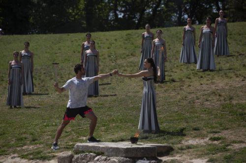 epa11279790 Greek actress Mary Mina (C-R), in the role of the High Priestess, passes the Olympic Flame to the first torchbearer Greek Rowing Olympic Champion Stefanos Ntouskos (C-L), during the rehearsal of the Olympic flame lighting ceremony for the Paris 2024 Summer Olympic Games, at the Ancient Olympia site in Peloponnese, southern Greece,15 April 2024....