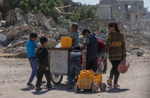 epa11327567 Internally displaced Palestinian children walk to fill water canisters after returning to Khan Younis town, southern Gaza Strip, 08 May 2024. The Israel Defence Forces (IDF) on 06 May called on residents of eastern Rafah to 'temporarily' evacuate to an expanded humanitarian area. On 07 May the IDF stated that its ground troops began an overnight...