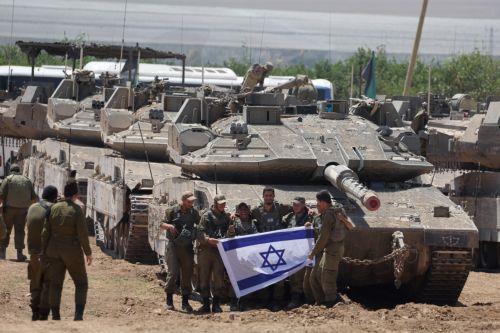 epa11328520 A group of Israeli soldiers holds an Israeli flag as they gather with military vehicles at an undisclosed position near the border fence with the Gaza Strip, in southern Israel, 09 May 2024. US Defense Secretary Austin at a Senate Appropriations Committee meeting on 08 May confirmed the Biden administration's decision to pause a shipment of...