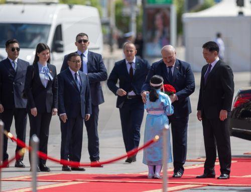 epa11386661 Belarusian President Alexander Lukashenko is greeted by a Mongolian girl in traditional costume beside Mongolian President Ukhnaagiin Khurelsukh (R) during a welcome ceremony at Sukhbaatar Square in Ulaanbaatar, Mongolia, 03 June 2024. Belarus President Alexander Lukashenko is in Mongolia for a state visit.  EPA/BYAMBASUREN BYAMBA-OCHIR