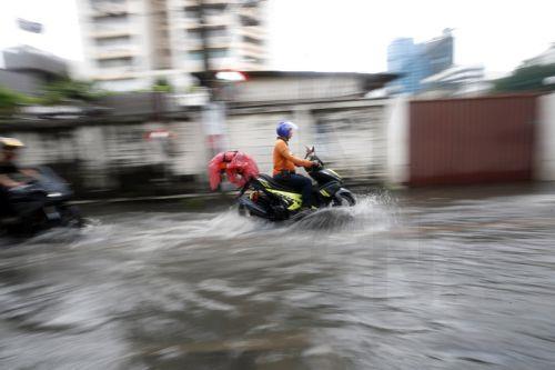 epa11581497 A photo taken with slow shutter speed shows motorists on motorcycles riding through a flooded road after a downpour in Bangkok, Thailand, 03 September 2024. The Thai Meteorological Department issued a public warning for heavy downpour to very heavy rainfall and advised residents to be observant of flash floods in Bangkok and across Thailand...