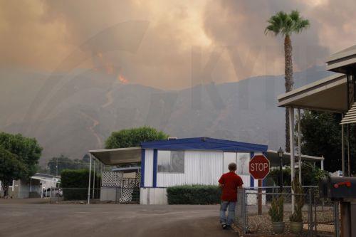 epa11597677 A person watches the â€˜Airport Fireâ€™ burn in the distance in Lake Elsinore, California, USA, 10 September 2024. The quick-moving brush fire that ignited Monday afternoon in Orange County, before growing to more than 34,000 acres as of Tuesday night, according to Cal Fire, has triggered mandatory evacuations in both Orange and Riverside...