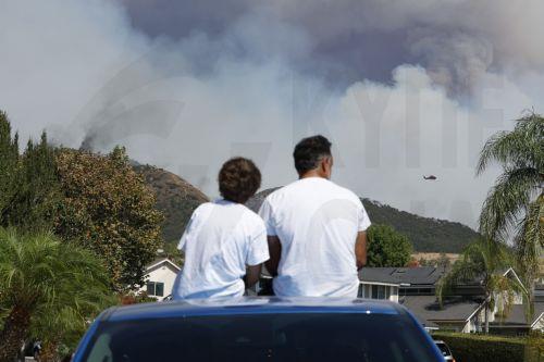 epa11597691 People watch the â€˜Airport Fireâ€™ burn in the distance from the rooftop of a car in Trabuco Canyon, California, USA, 10 September 2024. The quick-moving brush fire that ignited Monday afternoon in Orange County, before growing to more than 34,000 acres as of Tuesday night, according to Cal Fire, has triggered mandatory evacuations in both...