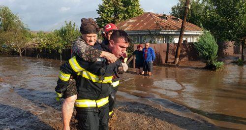 epa11603983 A handout photo made available by the Romanian General Inspectorate for Emergency Situations (IGSU) shows a Romanian rescuer carrying an elderly woman on his back out of a flooded street while a couple of neighbors (background) look on in front of their house, in the flood-affected village of Pechea, near Galati city, Romania, 14 September 2024....