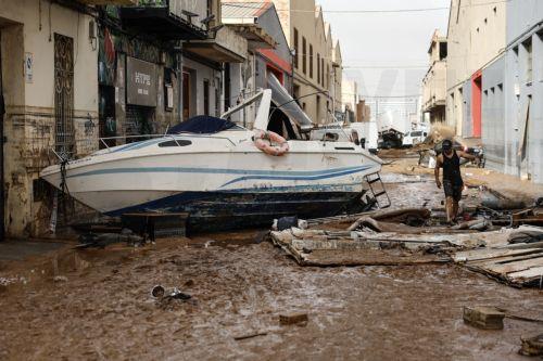 epa11692726 A person walks past a damaged boat in the flood-hit municipality of Sedavi, in the province of Valencia, eastern Spain, 30 October 2024. The intense rainfall impacting the eastern part of the country resulted in at least 70 lives being lost in the province of Valencia and neighboring provinces due to the flooding. The State Meteorological Agency...