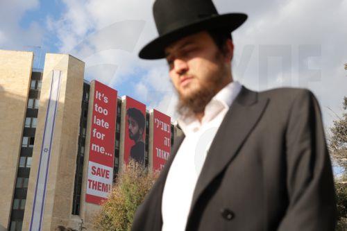 epa11756378 A person walks past a large billboard hanging from a building showing an image of Israeli hostage Hersh Goldberg-Polin, who was killed in captivity, reading 'It's too late for me... save them!', calling for the release of Israeli hostages held by Hamas in Gaza, in Jerusalem, 04 December 2024. According to Israel's military, around 100 Israeli...