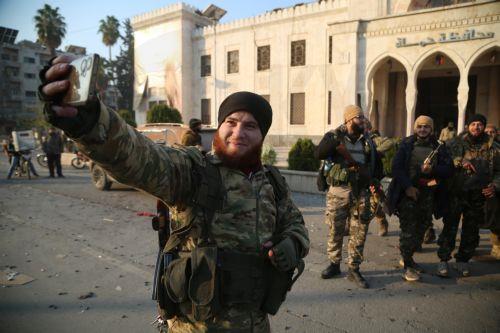 epa11760246 Opposition fighters pose for a selfie in front of a Syrian government building after they entered the city of Hama, Syria, 06 December 2024. Syrian opposition forces, led by the Islamist militant group Hayat Tahrir al-Sham (HTS), launched an offensive on 27 November, triggering counterattacks by the Syrian regime forces as well as Russian and...