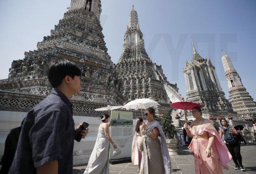 epa11808583 Foreign tourists dressed in Thai traditional costumes visit the Temple of Dawn, or Wat Arun, in Bangkok, Thailand, 06 January 2025. The Thai government has unveiled the 'Amazing Thailand Tourism 2025' campaign, a tourism strategy to boost tourism with the target to attract over 35 million international tourists to visit the kingdom in 2025 aimed...