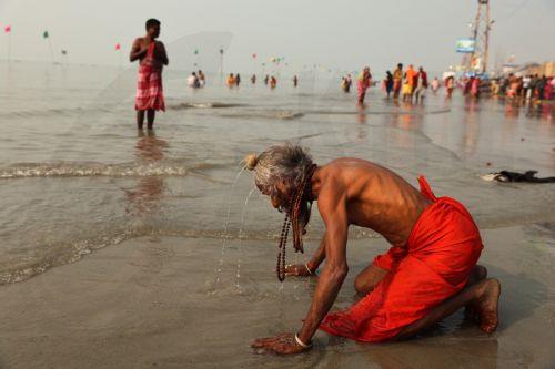 epa11821673 A Hindu monk takes a holy dip in the Bay of Bengal during the second day of the Ganga Sagar fair on Sagar Island, India, 13 January 2025. The fair is an annual gathering of Hindu pilgrims during Makar Sankranti to take a dip in the sacred waters of the Ganga River before it merges into the Bay of Bengal.  EPA/PIYAL ADHIKARY