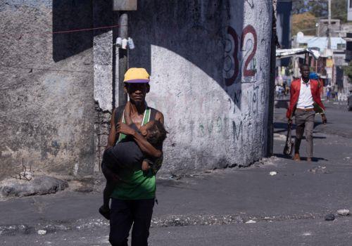 epa11920472 GRAPHIC CONTENT - A man carries a child in the Fort National neighborhood in Puerto Principe, Haiti, 23 February 2025. Several alleged gang members were lynched during a day of protests against insecurity in the nation, overwhelmed by a deep crisis that has worsened in recent years due to the violence of armed gangs, whose actions caused more...