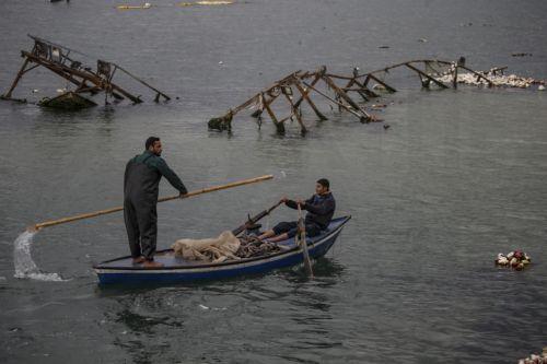 epaselect epa11922696 People on a small rowboat look around the water near destroyed ships of Palestinian fishermen floating on the surface of the water during the conflict in the destroyed Gaza port amid a ceasefire between Israel and Hamas, in Gaza City, northern Gaza Strip, 24 February 2025. Israel and Hamas implemented the first phase of a hostage...