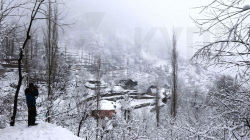 epa11929374 A person takes photos of a snow-covered area on the outskirts of Srinagar, India, 28 February 2025. The plains and upper reaches received fresh snowfall and rain, bringing much-needed relief from a prolonged dry spell.  EPA/FAROOQ KHAN