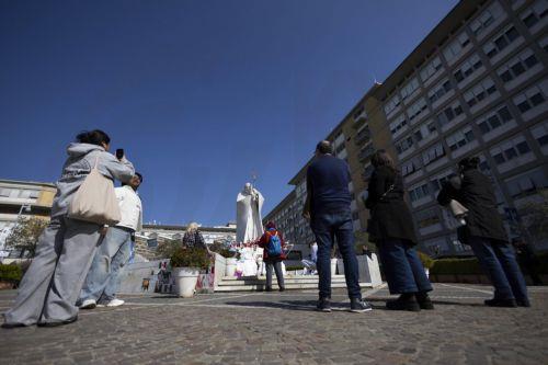epa11947146 People look at the statue of Pope John Paul II outside the Gemelli University Hospital, where Pope Francis is hospitalized, in Rome, Italy, 07 March 2025. The pontiff was admitted to Rome's Gemelli Hospital on 14 February, due to a respiratory tract infection.  EPA/MASSIMO PERCOSSI