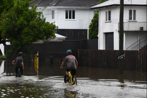 epa11953119 A person rides their bicycle through flooding in Newmarket, Brisbane, Australia, 10 March 2025. A cyclone has been downgraded to a tropical low but its impact is still being felt with a region reeling from major flooding with more wild weather forecast.  EPA/JONO SEARLE AUSTRALIA AND NEW ZEALAND OUT