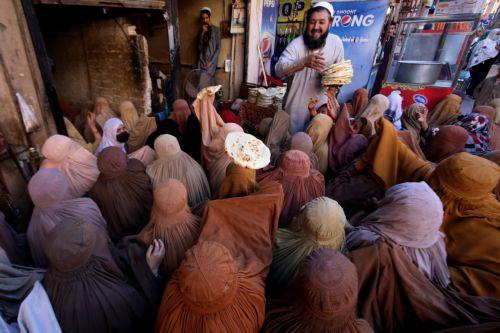 epa11953585 A man distributes free bread to burqa-clad women to break their fast during the fasting month of Ramadan in Peshawar, Pakistan, 10 March 2025. Muslims around the world observe the holy month of Ramadan by praying at night and abstaining from food and drink between sunrise and sunset.  EPA/ARSHAD ARBAB