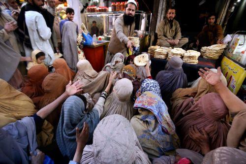 epa11953593 A man distributes free bread to burqa-clad women to break their fast during the fasting month of Ramadan in Peshawar, Pakistan, 10 March 2025. Muslims around the world observe the holy month of Ramadan by praying at night and abstaining from food and drink between sunrise and sunset.  EPA/ARSHAD ARBAB