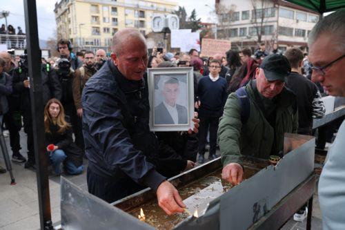 epa11969797 A man lights a candle while holding a photo of his relative, a victim who lost his life in the fire in the 'Club Pulse' night club in Kocani, Republic of North Macedonia, 17 March 2025. A fire at a discotheque in Kocani in the early hours of 16 March 2025 claimed the lives of at least 59 people and left over 100 injured, according to initial...
