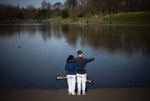epa11989609 People look out over Sefton Park boating lake in Liverpool, Britain, 26 March 2025.  EPA/ADAM VAUGHAN