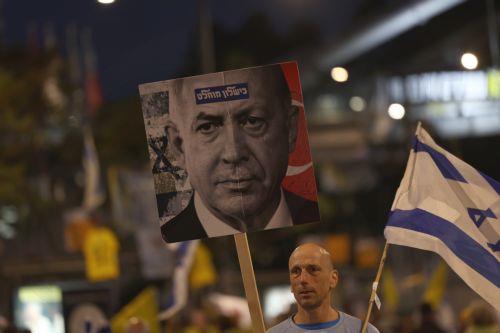 epa12012398 A demonstrator holds up a placard showing Israeli Prime Minister Benjamin Netanyahu and reading 'Complete failure' as families of Israeli hostages held by Hamas in Gaza, their supporters, and anti-government activists take part in a protest calling for the return of the hostages and against the Netanyahu Government, outside the Kirya military...