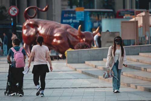 epa12020156 A woman walks past bull statue on the Bund in Shanghai, China, 09 April 2025. The USA have imposed a 104 percent tariff on some Chinese imports effective 09 April.  EPA/ALEX PLAVEVSKI