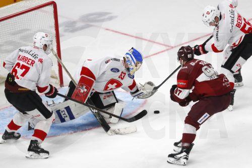epa12054792 Latvia's Haralds Egle in action against Switzerland's goalkeeper Leonardo Genoni, Roger Karrer (L), and Tim Berni (R) during the friendly international ice hockey match between Latvia and Switzerland in Riga, Latvia, 25 April 2025.  EPA/TOMS KALNINS