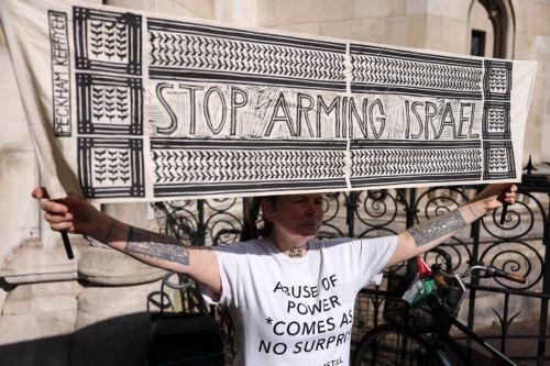 epa12095687 A protester holds up a banner while taking part in a demonstration against selling arms to Israel at the Royal Courts of Justice in London, Britain, 13 May 2025. A four-day judicial review brought by Palestinian rights group Al-Haq and the Global Legal Action Network (GLAN) starts in the High Court on 13 May, with human rights' groups and...