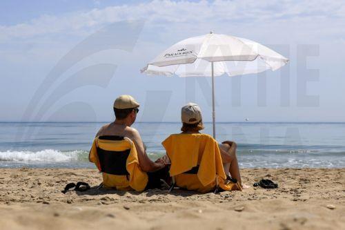 epa12196494 People rest in El Saler beach during hot weather in Valencia, Spain, 25 June 2025.  EPA/KAI FORSTERLING