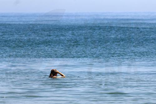epa12196495 A beach-goer swims in El Saler beach during hot weather in Valencia, Spain, 25 June 2025.  EPA/KAI FORSTERLING