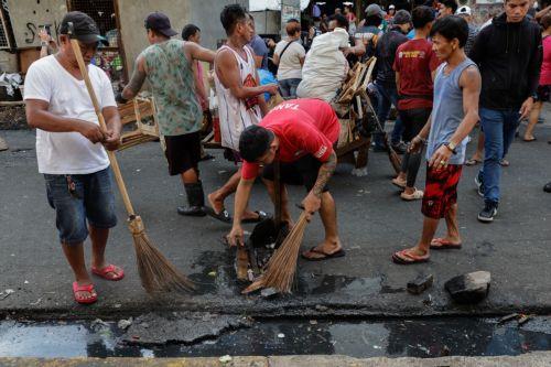 epa12216963 Villagers clean a clogged sidewalk canal at a public market area in Manila, Philippines 05 July 2025. The mayor of Manila ordered intensified waste collection and cleanup operations of waterways, canals and populated areas beginning 05 July, after declaring a health emergency on just his first week as newly-elected city head.  EPA/ROLEX DELA PENA