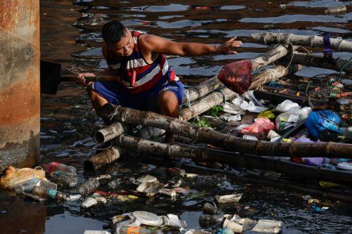 epa12216972 A villager on a bamboo raft collects trash along a creek in Manila, Philippines 05 July 2025. The mayor of Manila ordered intensified waste collection and cleanup operations of waterways, canals and populated areas beginning 05 July, after declaring a health emergency on just his first week as newly-elected city head.  EPA/ROLEX DELA PENA