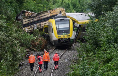 epa12267656 Emergency workers of German Railroad company (DB) stand on the railway track in front a derailed passenger train near Riedlingen, Germany, 28 July 2025. According to the police and fire department, three people died and around 50 were injured.  EPA/RONALD WITTEK