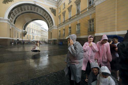 epa12275138 People take shelter from the rain under the General Staff Arch on Palace Square in central St. Petersburg, Russia, 31 July 2025.  EPA/ANATOLY MALTSEV