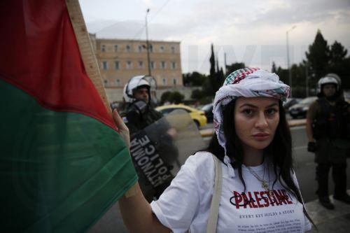 epa12275624 A Palestinian living in Greece holds a Palestinian flag in front of police officers as she takes part in a rally against Israel's ongoing operations in the Gaza Strip, in central Athens, Greece 31 July 2025.  EPA/YANNIS KOLESIDIS