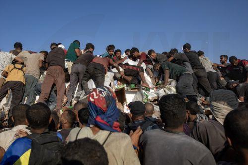 epa12283325 Internally displaced Palestinians climb aid trucks to get food near a food distribution point in the Morag corridor, south of Khan Younis, in the southern Gaza Strip, 04 August 2025.  EPA/HAITHAM IMAD