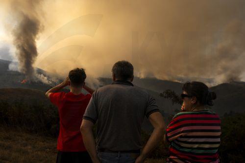 epaselect epa12292300 Residents watch as smoke rises from a fire that broke out late the previous day in the surroundings of Maceda in Galicia, northwestern Spain, 10 August 2025. The fire ignited at five or six points almost simultaneously, prompting the Galician government to declare an emergency level 2 due to its proximity to A Teixeira, a neighborhood...