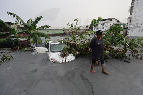 epa12401271 A man walks past a damaged vehicles partially buried by silt in the aftermath of Super Typhoon Ragasa in Guangfu Township, Hualien County, Taiwan, 24 September 2025. At least 14 people have died, 32 were injured and more than 150 are missing in the eastern county after a barrier lake in the mountains overflowed and inundated the township during...