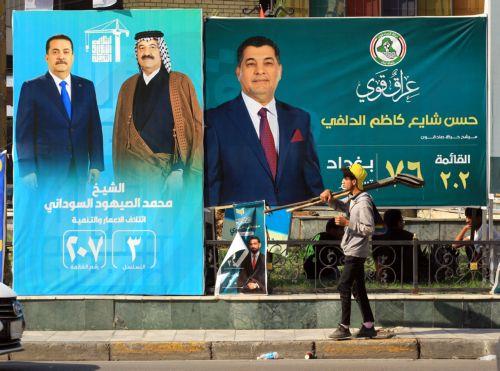 epa12510563 A young Iraqi worker walks past election campaigning posters ahead of the parliamentary elections in Baghdad, Iraq, 07 November 2025. Iraq is preparing to hold legislative elections on 11 November 2025.  EPA/CEERWAN AZIZ
