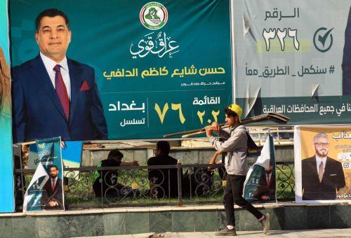 epa12510564 A young Iraqi worker walks past election campaigning posters ahead of the parliamentary elections in Baghdad, Iraq, 07 November 2025. Iraq is preparing to hold legislative elections on 11 November 2025.  EPA/CEERWAN AZIZ